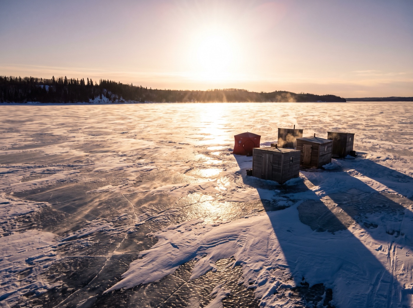 Ice fishing shacks on a frozen lake in blinding off-snow glare